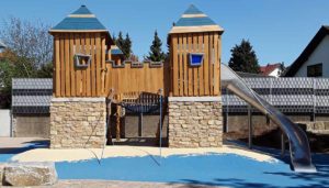 Spielplatzgeräte: Spielturm mit Holzelementen und Rutsche. Spielplatzgeräte für den öffentlichen Raum