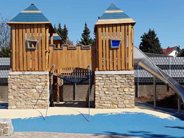 Spielplatzgeräte: Spielturm mit Holzelementen und Rutsche. Spielplatzgeräte für den öffentlichen Raum